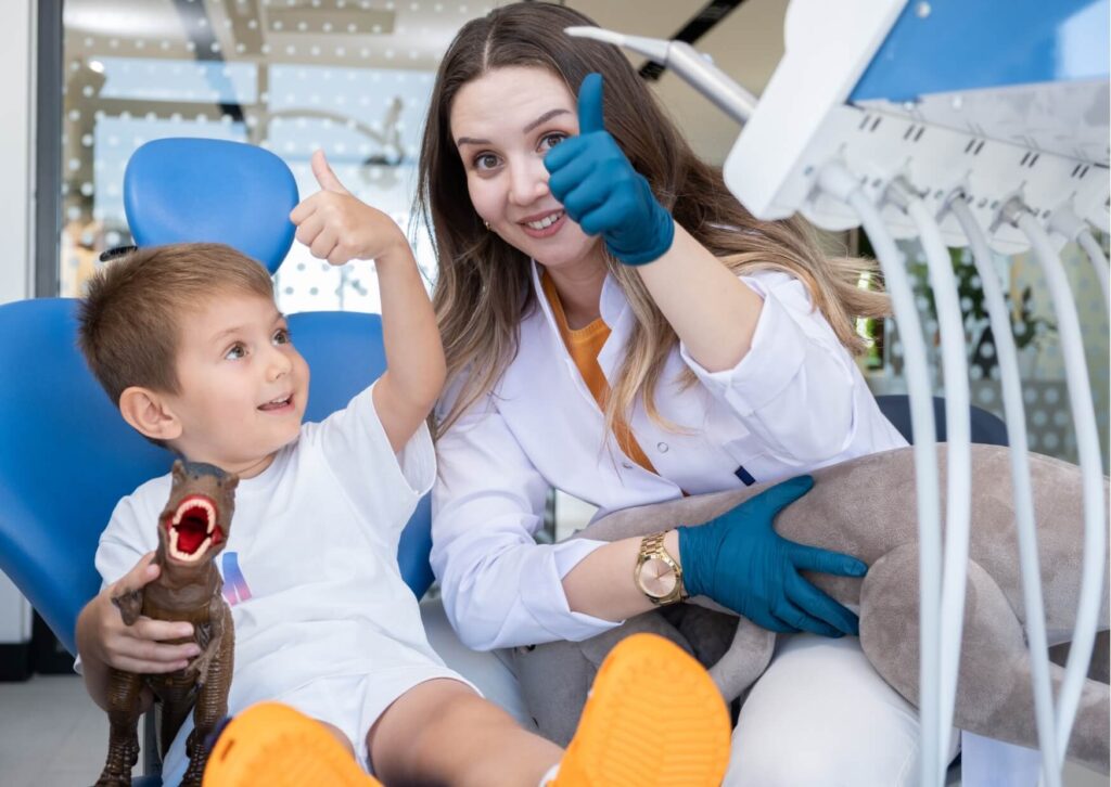 Pediatric dentist reassuring a young patient during a dental visit while discussing kids dental spacers and healthy smile development.
