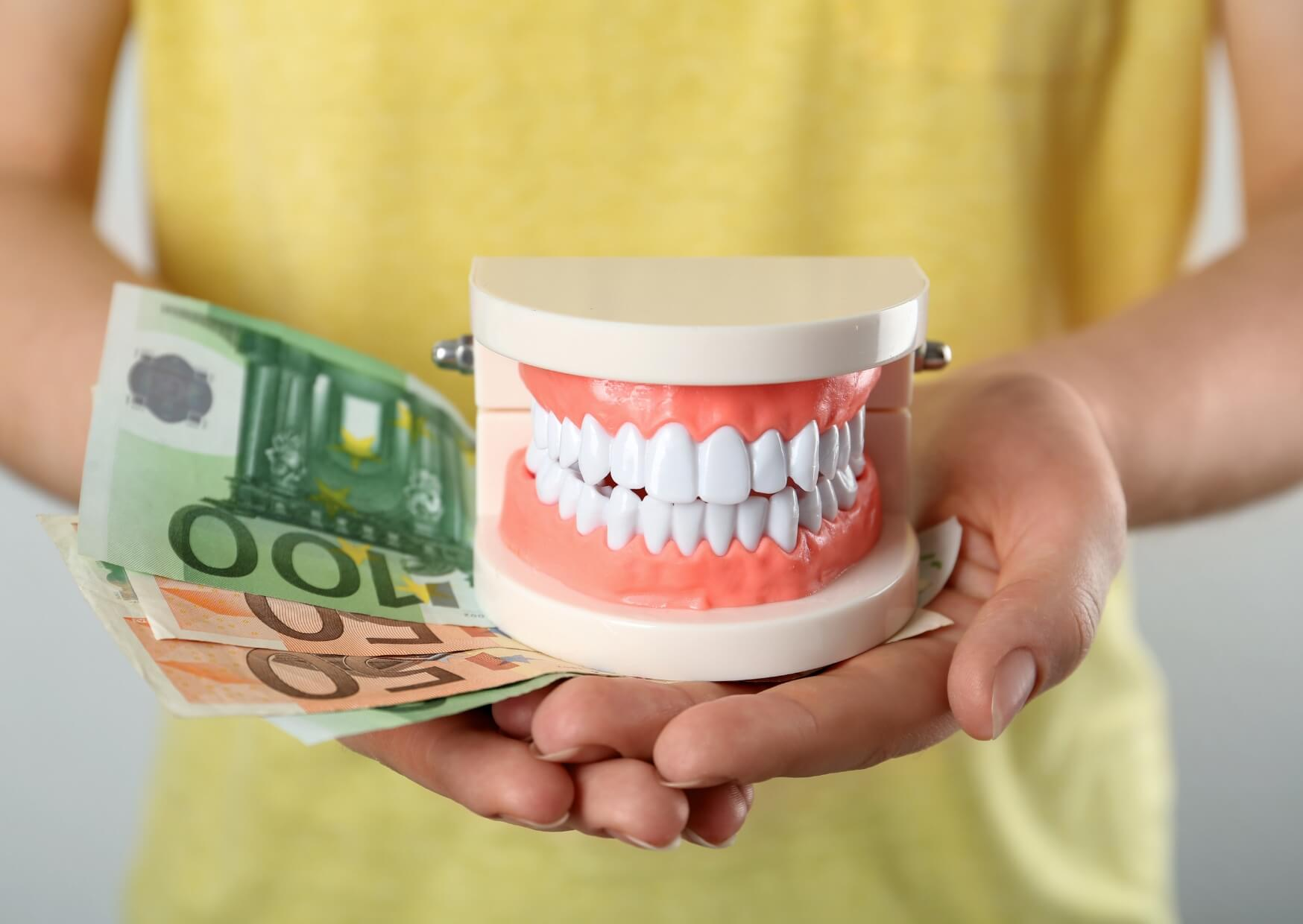 Dental model with banknotes illustrating how veneer costs by location can vary depending on the dentist, materials, and region.