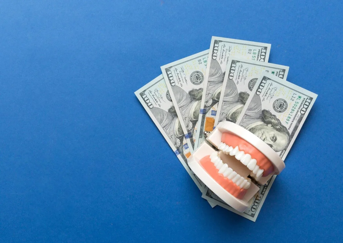 Dental model with money representing the cost of full mouth dental implants.