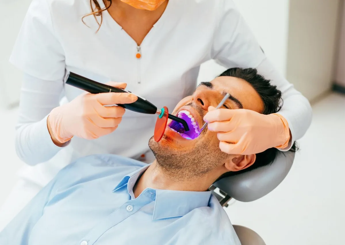 Dentist applying tooth-colored resin during a teeth bonding procedure.