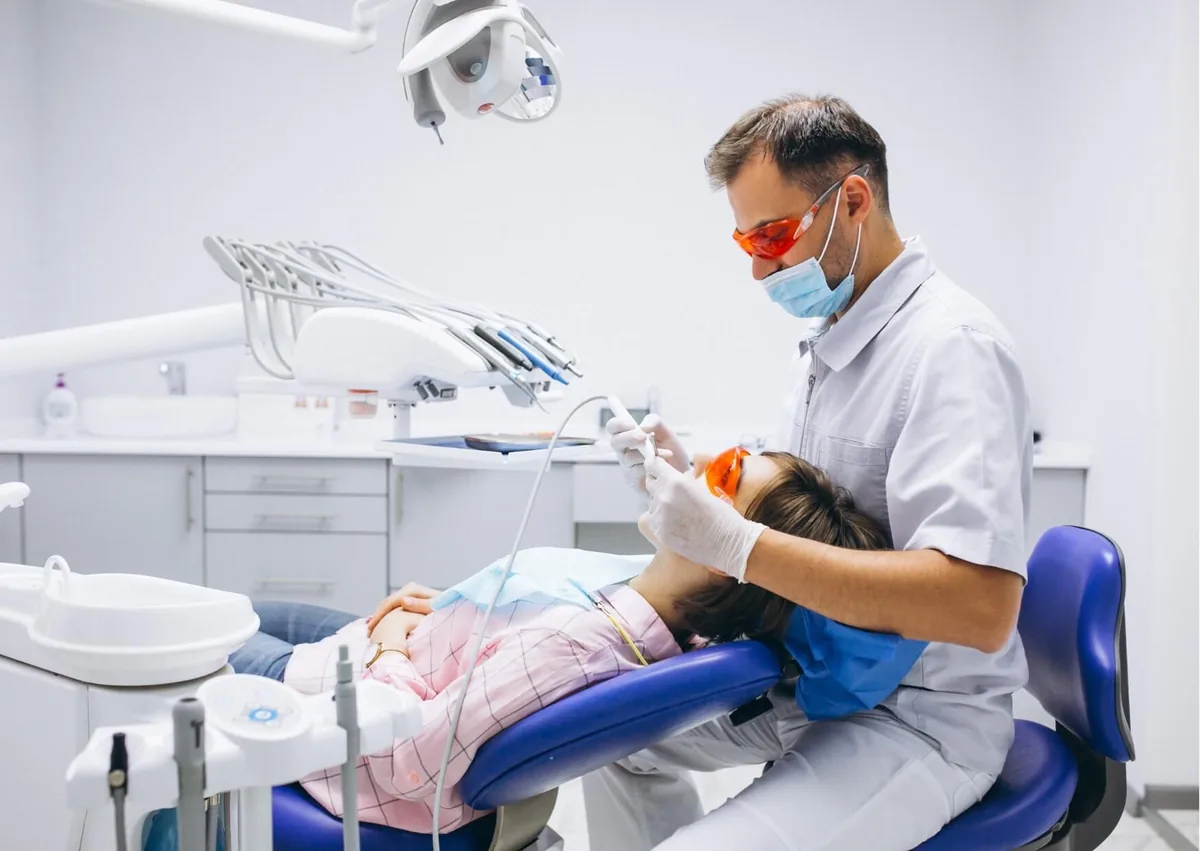 Dentist removing plaque from a patient’s teeth during a professional dental cleaning.