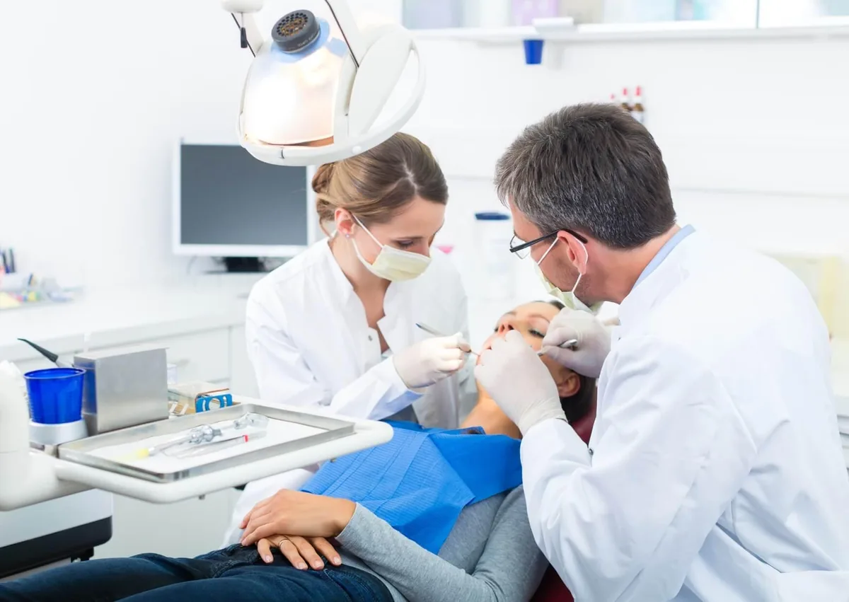 Dentist and assistant performing a dental procedure as part of the tooth implant timeline.