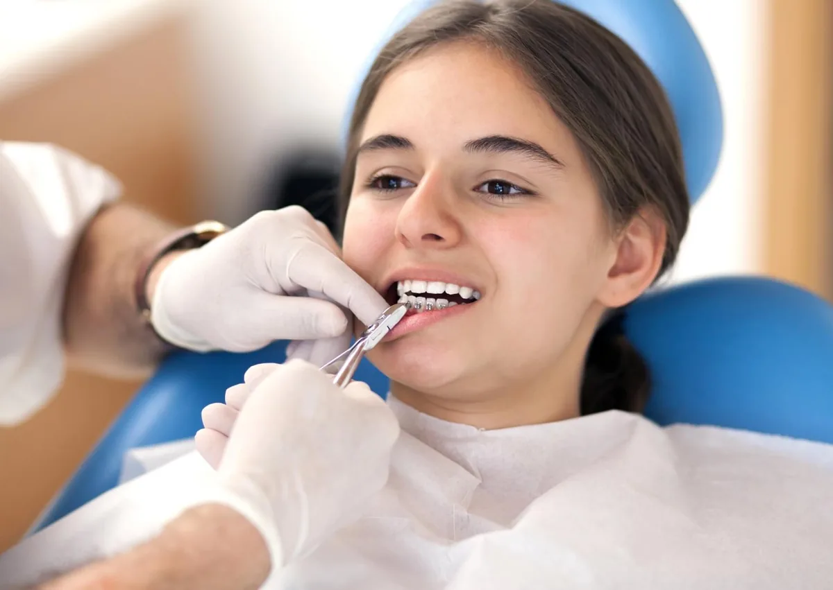 Orthodontist adjusting a patient’s braces during treatment covered by dental insurance.
